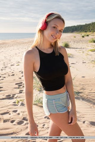 Блондинка с наушниками на пляже гладит без трусиков писюню и соски